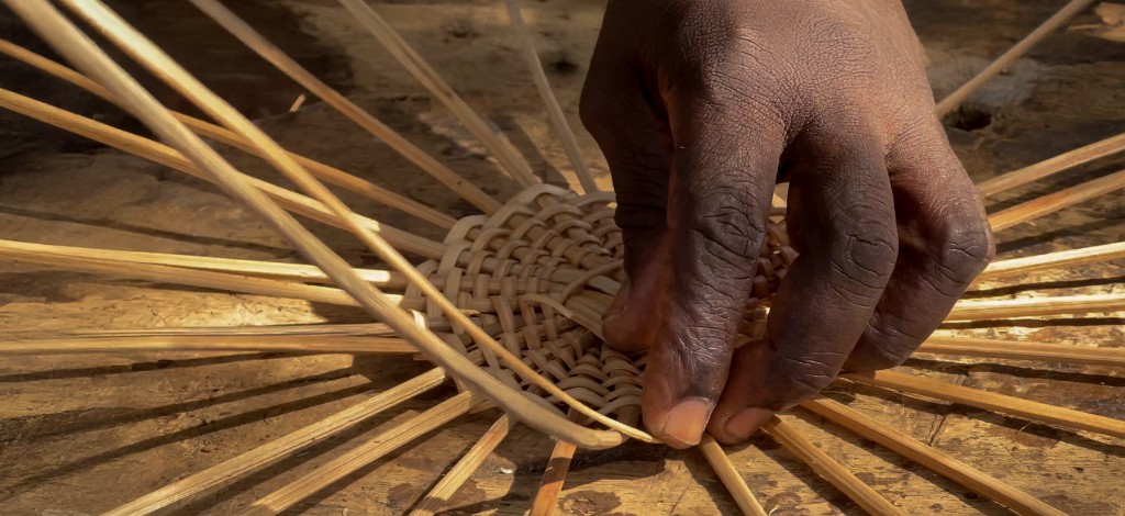Hands weaving a rattan basket